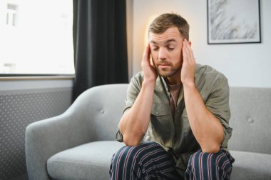 hasta adam yatağında kafasını elinde oturuyor..