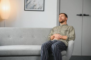 Evde oturma odasında bir kanepede oturan mide ağrısı acı Adam