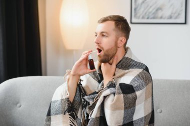 Rhinitis, ilaç ve sağlık konsepti - evde ağız spreyi kullanan hasta adam.