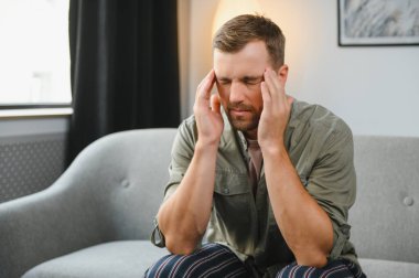 hasta adam yatağında kafasını elinde oturuyor..