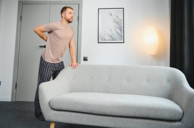 Genç adam ağır mobilyalar taşıyan sonra sırt ağrısı acı