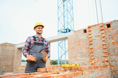 Construction worker man in work clothes and a construction helmet. Portrait of positive male builder in hardhat working at construction site