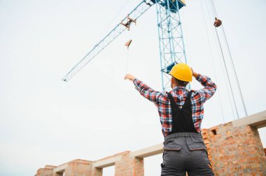 Construction worker in uniform and safety equipment have job on building. Industrial theme.