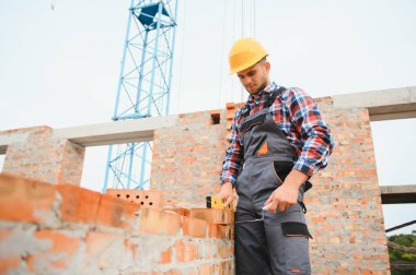 Installing brick wall. Construction worker in uniform and safety equipment have job on building.