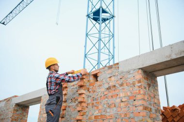 Installing brick wall. Construction worker in uniform and safety equipment have job on building.