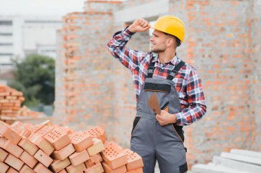 Construction worker in uniform and safety equipment have job on building. Industrial theme.