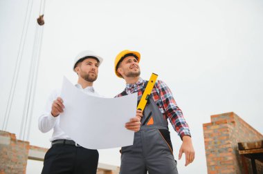 İnşaat mühendisi ve ustabaşı açık hava inşaatı için çalışma planlarını tartıştılar..