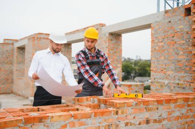 İnşaat mühendisi ve ustabaşı açık hava inşaatı için çalışma planlarını tartıştılar..