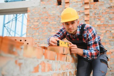 Üniformalı inşaat işçisi ve güvenlik ekipmanı inşaatında çalışıyor.