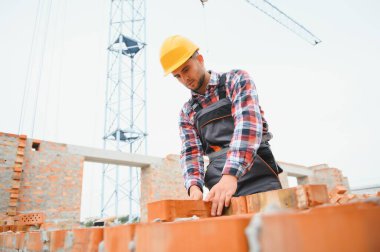 Installing brick wall. Construction worker in uniform and safety equipment have job on building.