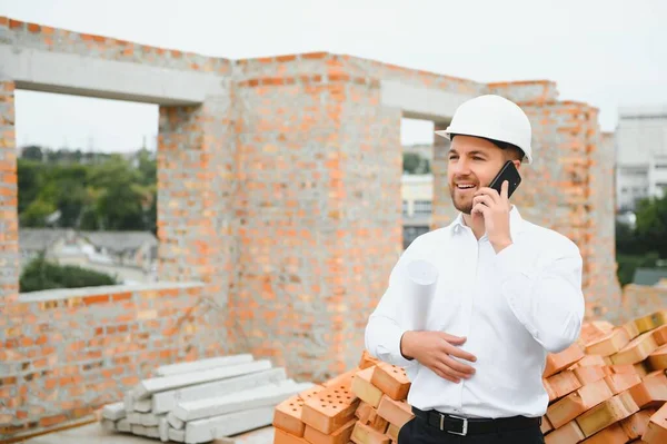 Engineering Consulting People on construction site holding blueprint in his hand. Building inspector. Construction site check drawing and business workflow of new building