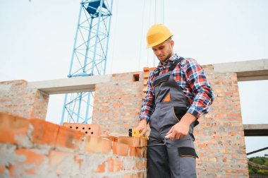 Construction worker in uniform and safety equipment have job on building. Industrial theme.