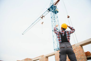 Üniformalı inşaat işçisi ve güvenlik ekipmanı inşaatında çalışıyor.