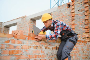 Üniformalı inşaat işçisi ve güvenlik ekipmanı inşaatında çalışıyor.