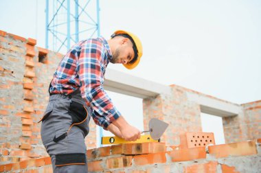 Construction worker man in work clothes and a construction helmet. Portrait of positive male builder in hardhat working at construction site