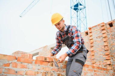 Busy with brick wall. Construction worker in uniform and safety equipment have job on building