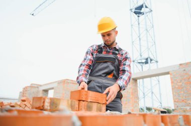 Installing brick wall. Construction worker in uniform and safety equipment have job on building.