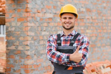 Sarı renkli başlık. Gündüz vakti inşaatta üniformalı genç bir adam çalışıyor.