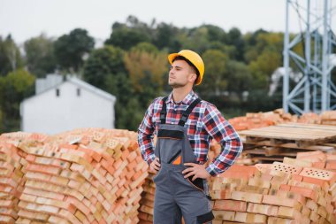 Construction worker man in work clothes and a construction helmet. Portrait of positive male builder in hardhat working at construction site