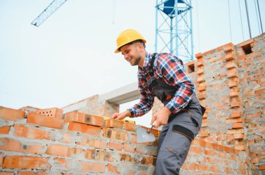 Installing brick wall. Construction worker in uniform and safety equipment have job on building.