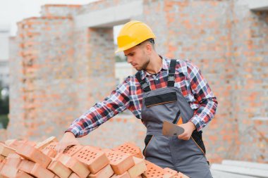 Construction worker in uniform and safety equipment have job on building. Industrial theme.