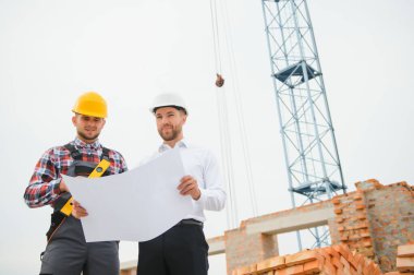 İnşaat mühendisi ve ustabaşı açık hava inşaatı için çalışma planlarını tartıştılar..