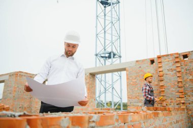 İnşaat alanında mavi baskı ile çalışan mühendis konsepti