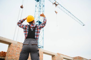 Construction worker in uniform and safety equipment have job on building. Industrial theme.