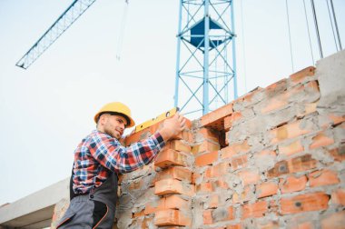 Communicating with crane guy. Construction worker in uniform and safety equipment have job on building