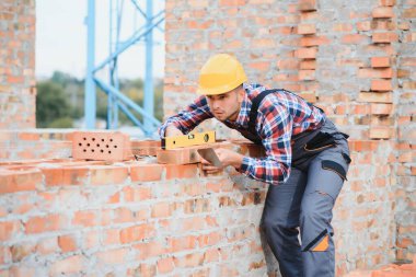 Construction worker man in work clothes and a construction helmet. Portrait of positive male builder in hardhat working at construction site