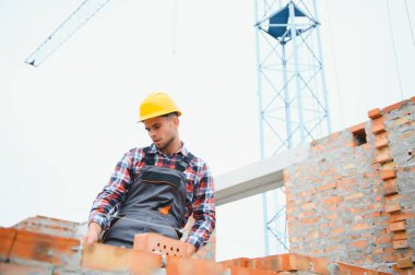 Construction worker man in work clothes and a construction helmet. Portrait of positive male builder in hardhat working at construction site