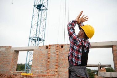 Vinçli adamla iletişim kuruyorum. Üniformalı inşaat işçisi ve güvenlik ekipmanı inşaatında çalışıyor