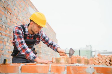 Installing brick wall. Construction worker in uniform and safety equipment have job on building.