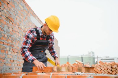 Construction worker man in work clothes and a construction helmet. Portrait of positive male builder in hardhat working at construction site