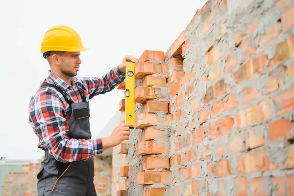 Sarı renkli başlık. Gündüz vakti inşaatta üniformalı genç bir adam çalışıyor.