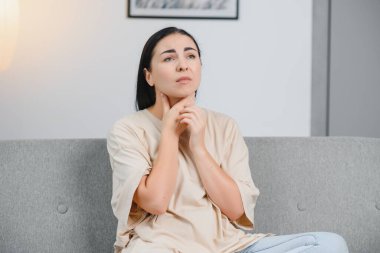 Sağlık, soğuk ve insanlar konsepti. Evinde boğazı ağrıyan üzgün, hasta bir Asyalı kadın.