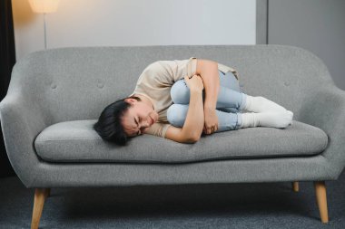 Yatak odasında regl sancısı çeken genç bir kadın.