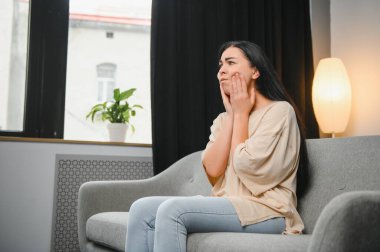 Şiddetli diş ağrısı olan bir kadın şişmiş yanağına dokunuyor. Diş çekildikten sonra kendini rahatsız hisseden genç bir kız. Diş sinirleri iltihaplanmış üzgün bir kadın ya da evdeki kanepede oturan korkunç bir diş ağrısı.