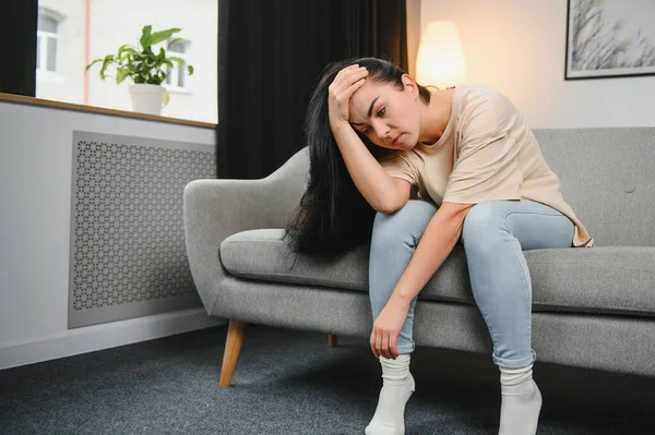 Üzgün, üzgün, çekici bir kadın evdeki kanepede ağlıyor. Yalnız hissediyor, yorgun ve endişeli. Akıl sağlığı, yalnızlık ve yalnızlık yüzünden depresyonda. Psikoloji, yalnızlık ve insanlar