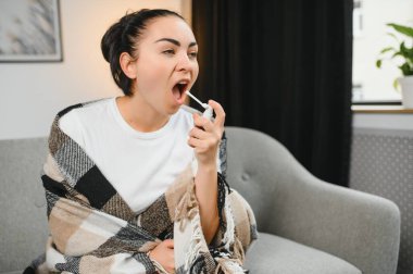 evde kanepede otururken püskürtme boğaz hasta genç kadın sıcak giysiler