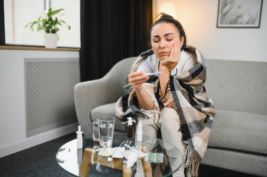 Grip ve grip. Hasta kadın üşütmüş, hasta olmuş. Battaniyeyle kaplanmış, burnunu silen ve termometreye bakan sağlıksız güzel bir kız. Sağlık hizmetleri kavramı