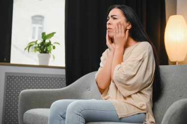 Şiddetli diş ağrısı olan bir kadın şişmiş yanağına dokunuyor. Diş çekildikten sonra kendini rahatsız hisseden genç bir kız. Diş sinirleri iltihaplanmış üzgün bir kadın ya da evdeki kanepede oturan korkunç bir diş ağrısı.