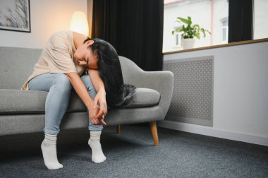 Üzgün, üzgün, çekici bir kadın evdeki kanepede ağlıyor. Yalnız hissediyor, yorgun ve endişeli. Akıl sağlığı, yalnızlık ve yalnızlık yüzünden depresyonda. Psikoloji, yalnızlık ve insanlar