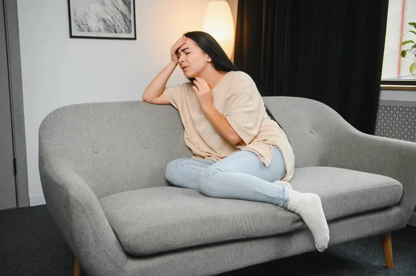 Kafasına dokunan yorgun bir kız, baş ağrısı, migren, evdeki kanepede oturmak. Depresyondaki genç kadın kayıp, keder ve travmayla baş ediyor. Sinir krizi, kriz konsepti