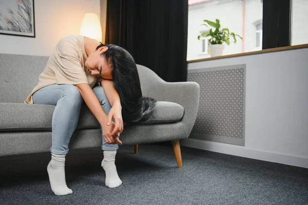 Üzgün, üzgün, çekici bir kadın evdeki kanepede ağlıyor. Yalnız hissediyor, yorgun ve endişeli. Akıl sağlığı, yalnızlık ve yalnızlık yüzünden depresyonda. Psikoloji, yalnızlık ve insanlar