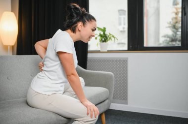 Güzel kız sırt ağrısı çekerken kapalı gözlerle yatakta oturuyor.