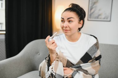 Sağlık, soğuk algınlığı ve insanlar konsepti - üzgün, hasta, genç kadın evde ağız spreyi kullanıyor..