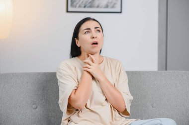 Çekici esmer boğaz ağrısı ile yatakta oturan.