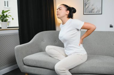 Güzel kız sırt ağrısı çekerken kapalı gözlerle yatakta oturuyor.