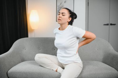 Güzel kız sırt ağrısı çekerken kapalı gözlerle yatakta oturuyor.